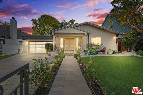 a view of a house with a small yard and a large tree
