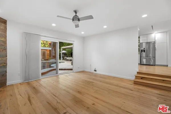 a view of an empty room with window and wooden floor