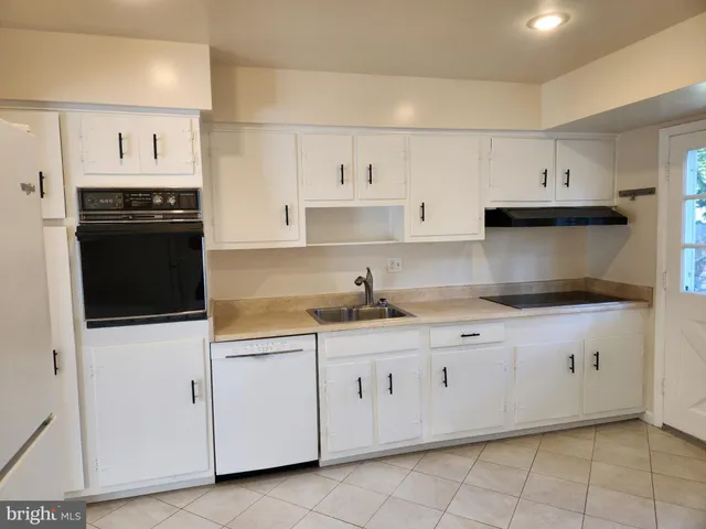 a kitchen with granite countertop white cabinets and black appliances