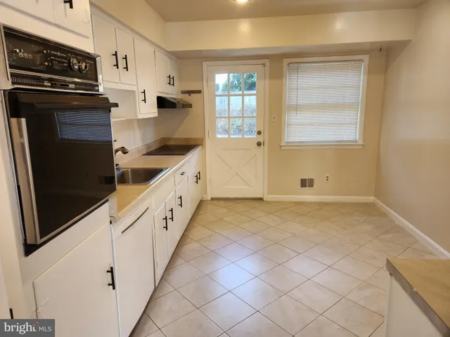 a kitchen with granite countertop white cabinets and refrigerator