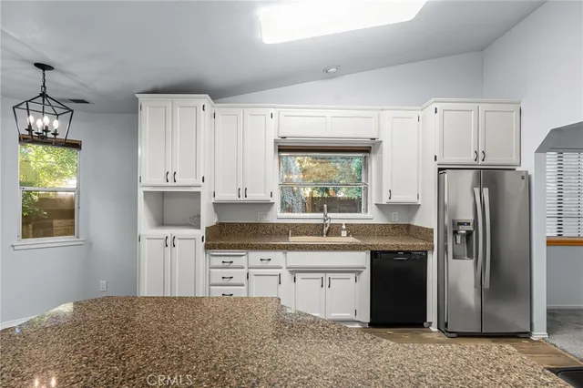 a view of an empty room with wooden floor and chandelier