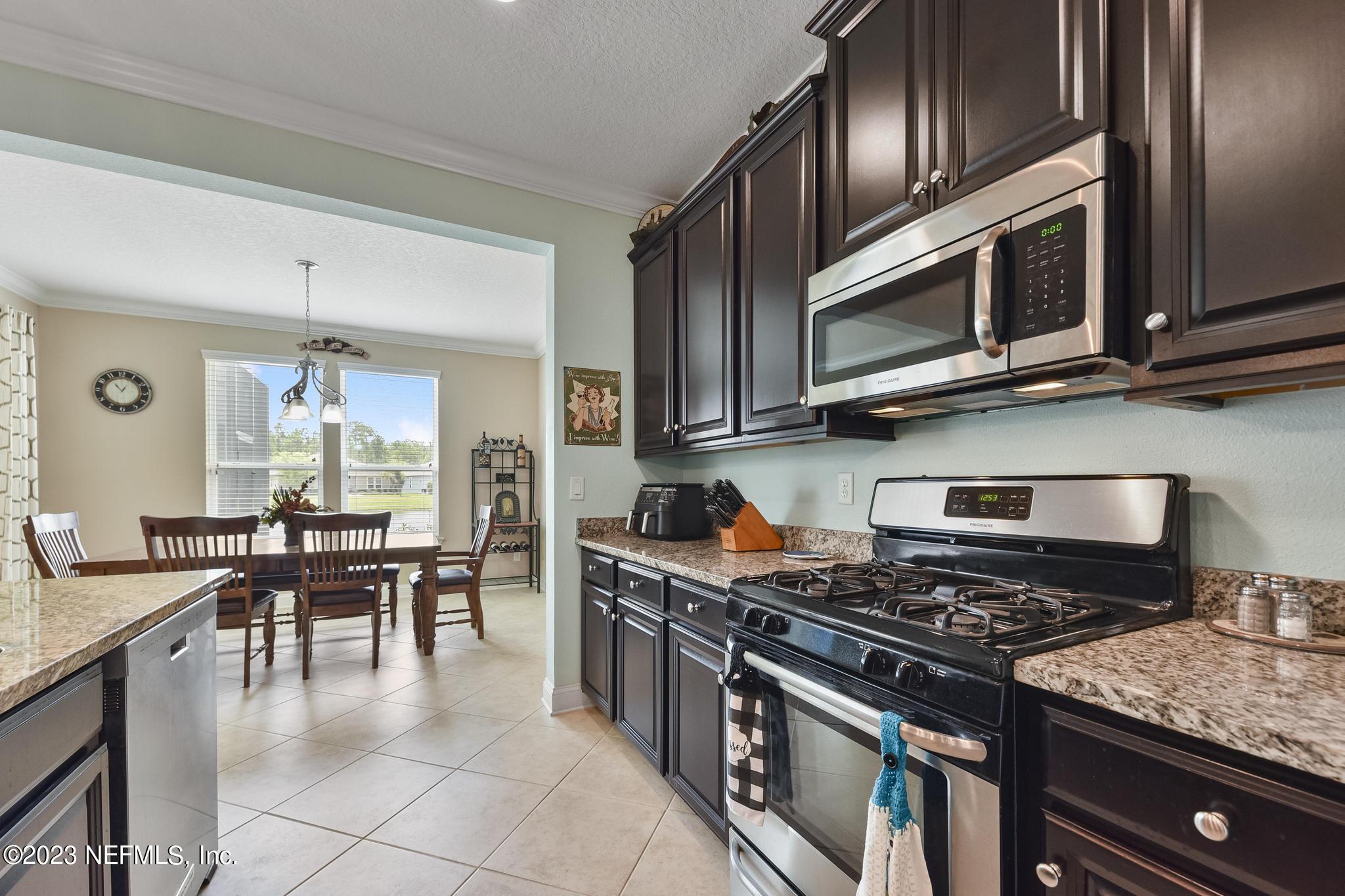 168 St Kitts Loop St. Augustine, FL 32092 - Photo 14 of 41 a kitchen with stainless steel appliances granite countertop a stove top oven a sink dishwasher a dining table and chairs with wooden floor