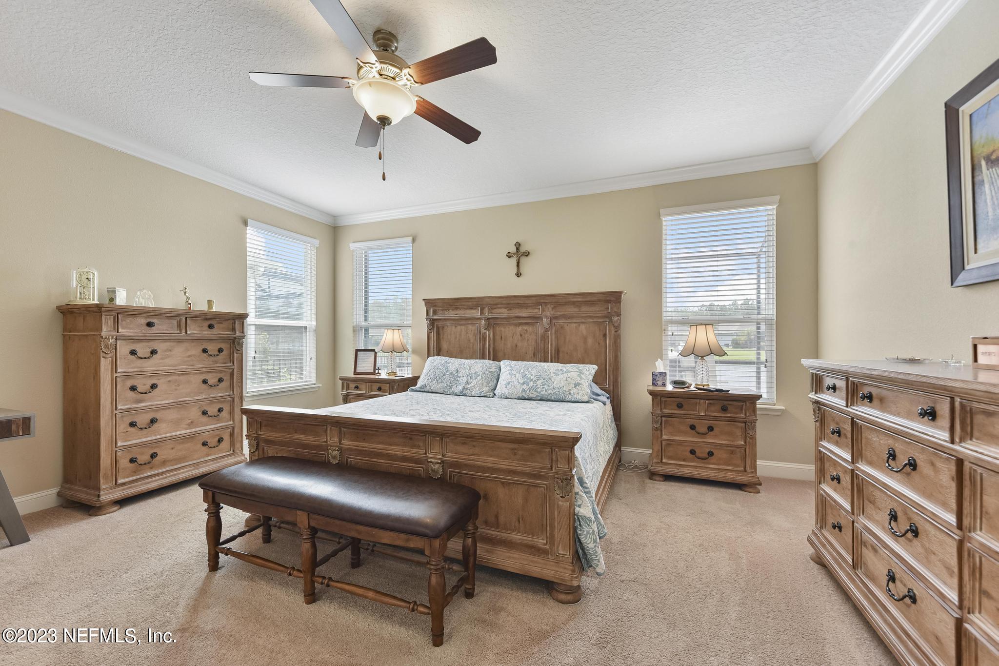 168 St Kitts Loop St. Augustine, FL 32092 - Photo 15 of 41 a bedroom with a bed a dresser and a chandelier