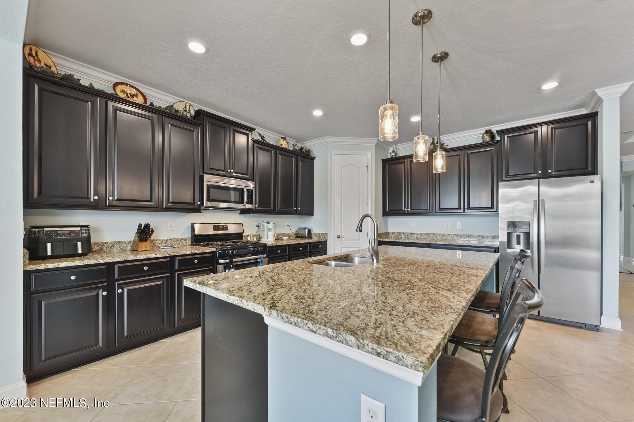 168 St Kitts Loop St. Augustine, FL 32092 - Photo 10 of 41 a kitchen with stainless steel appliances granite countertop a sink a stove a refrigerator cabinets and a kitchen island