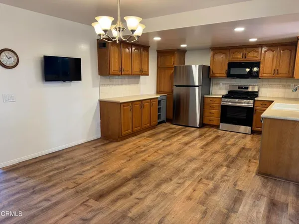 a kitchen with stainless steel appliances granite countertop a refrigerator a stove top oven a sink dishwasher and wooden cabinets