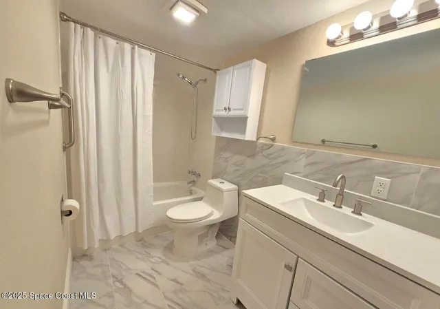 a bathroom with a sink a toilet a mirror and shower
