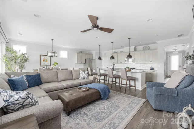 a living room with furniture kitchen view and a chandelier