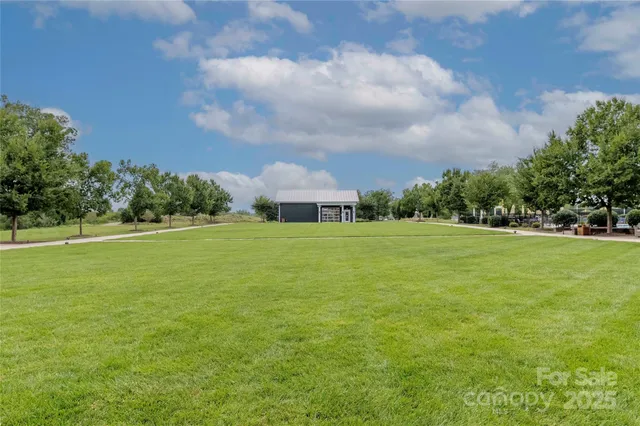 a view of a green field with house in the background