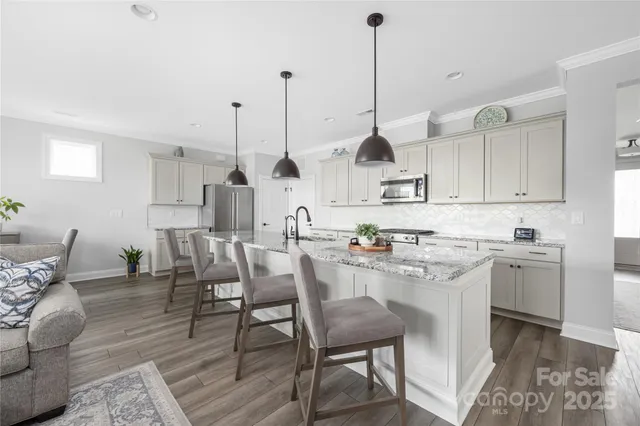 a kitchen with kitchen island a dining table chairs sink and cabinets