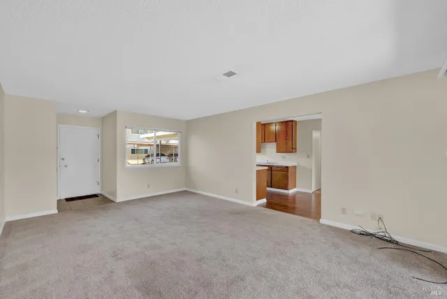 an empty room with a ceiling fan and carpet