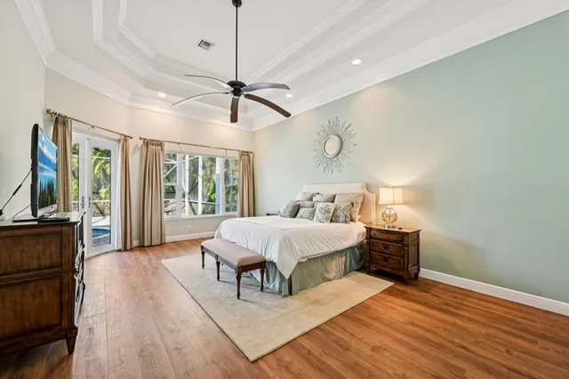 a spacious bedroom with a bed a chandelier and flat screen tv