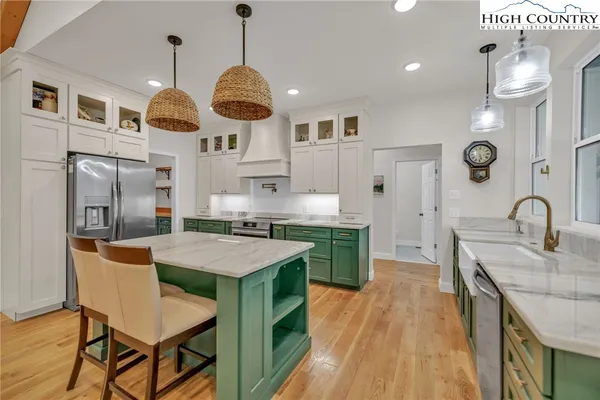 a kitchen with stainless steel appliances granite countertop a stove a refrigerator a oven a dining table and chairs with wooden floor