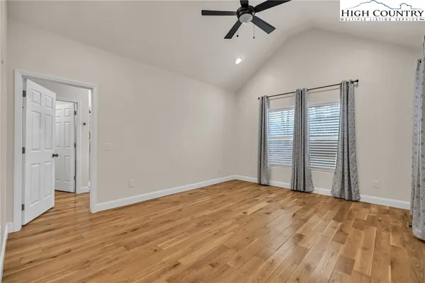 an empty room with wooden floor fan and windows
