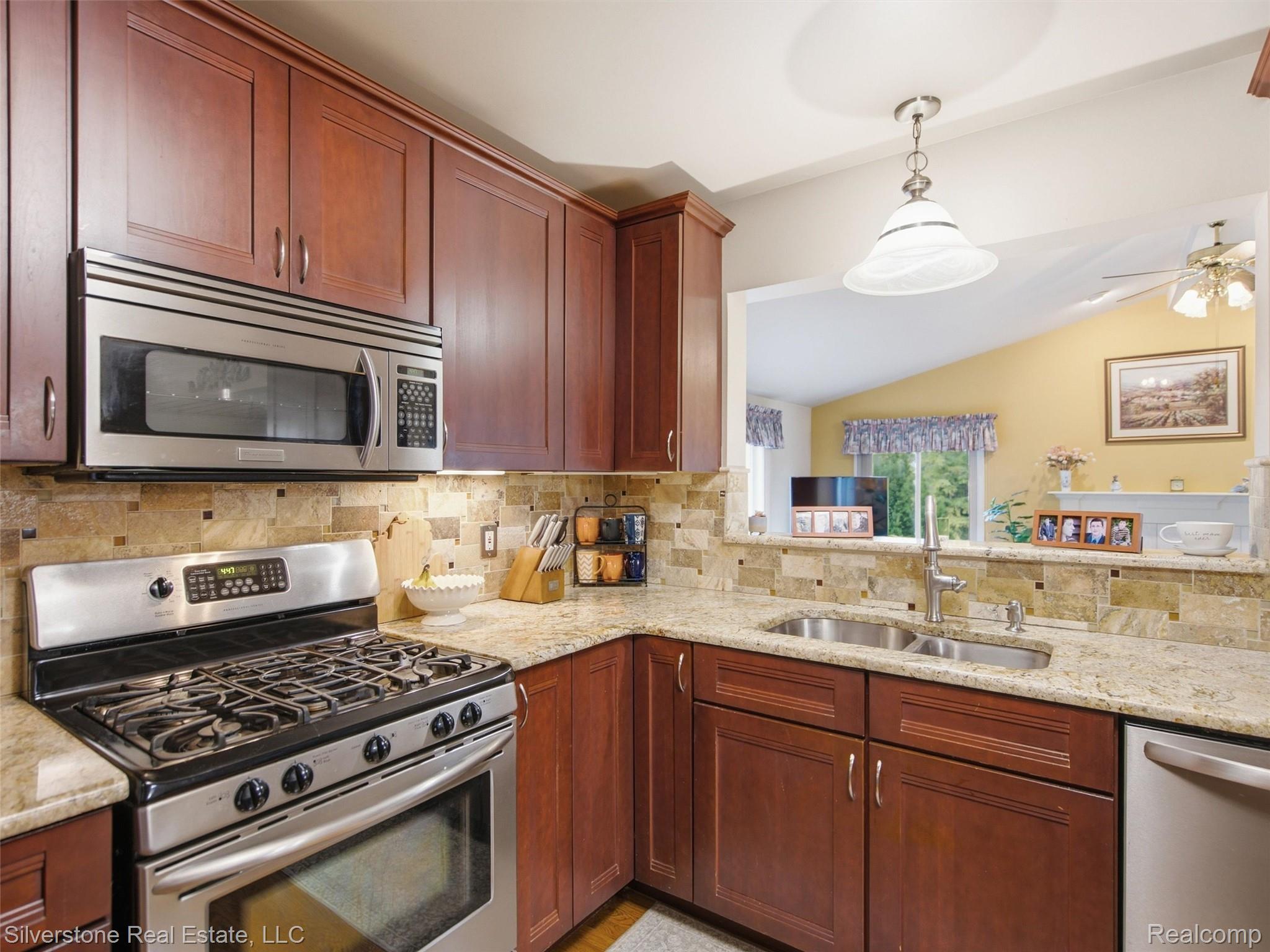 6577 Edith Court Troy, MI 48085 - Photo 25 of 61 Kitchen featuring rich wood cabinetry, stainless steel appliances, granite countertops, a stone tile backsplash, and a pass-through opening