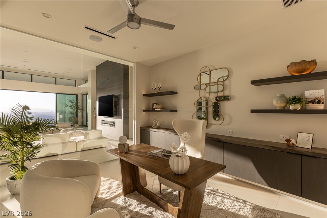 563 Grand Rim Drive Henderson, NV 89012 - Photo 17 of 70 An inviting study area seamlessly transitions to a bright living space through expansive glass doors, offering panoramic views.