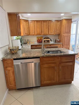 a kitchen with granite countertop a sink a stove a washer dryer and white cabinets