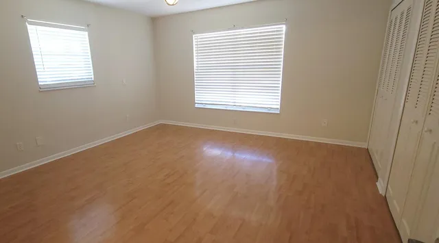 a view of an empty room with wooden floor and a window