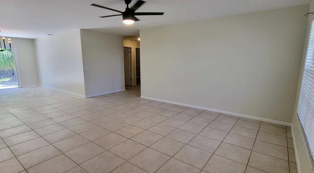 an empty room with ceiling fan and window