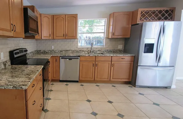 a kitchen with stainless steel appliances granite countertop a refrigerator sink and microwave
