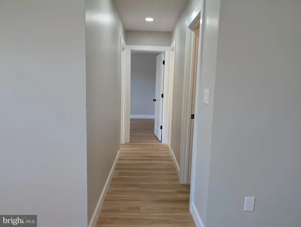 a view of a hallway with wooden floor and a bathroom