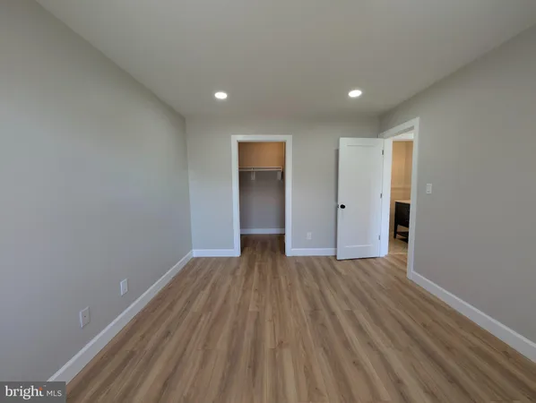 a view of an empty room with wooden floor and closet