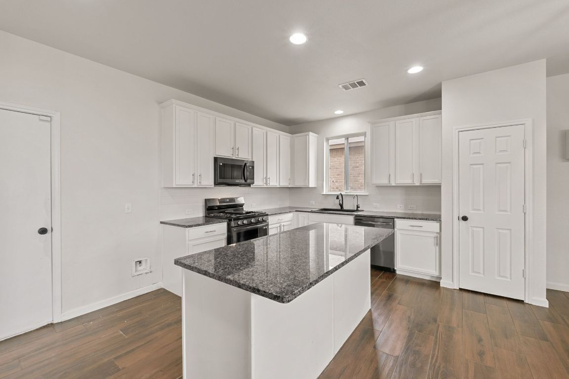 240 Nectar Drive Buda, TX 78610 - Photo 10 of 37 a kitchen with stainless steel appliances granite countertop a stove a sink and a refrigerator