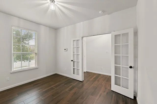 a view of an empty room with wooden floor and a window
