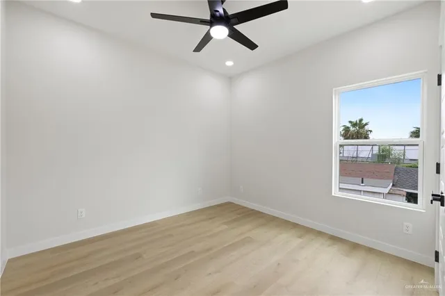 an empty room with a window and ceiling fan
