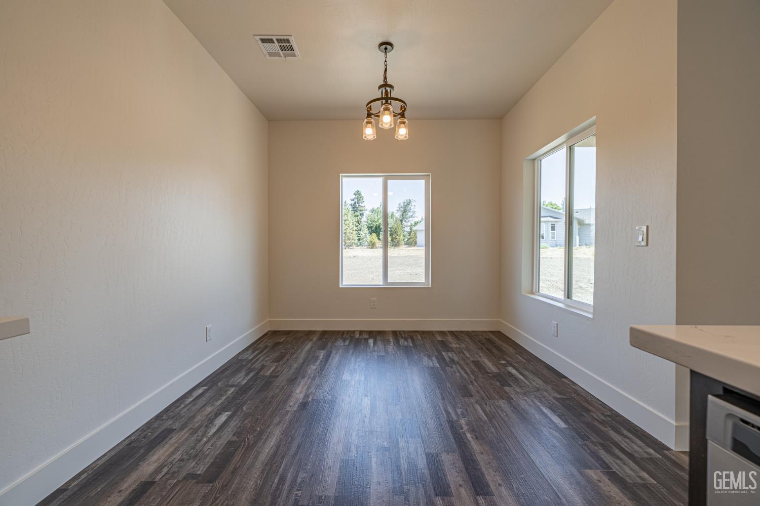 Undisclosed Address Tehachapi, CA 93561 - Photo 11 of 20 an empty room with wooden floor chandelier and windows