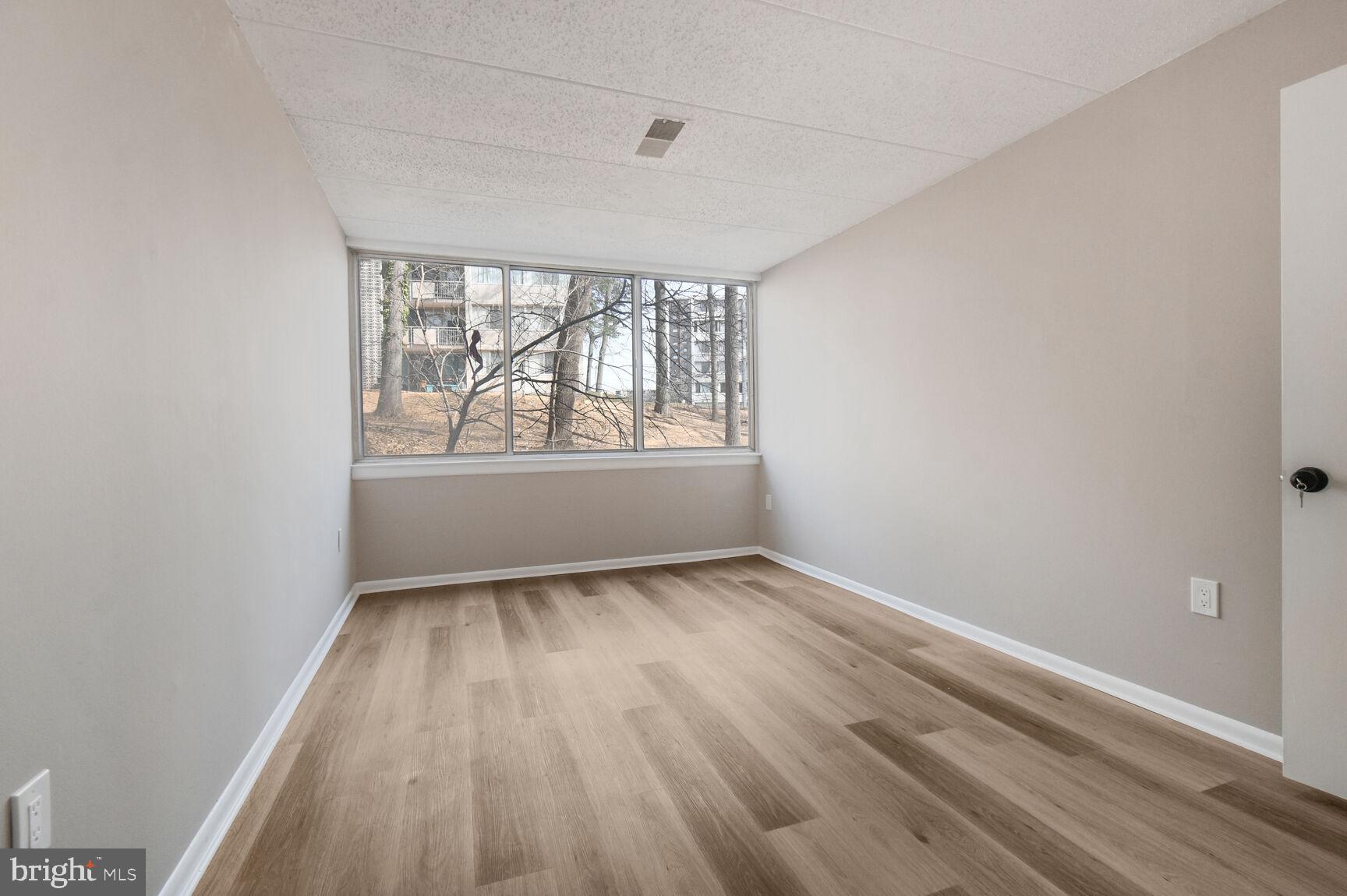 1804 Metzerott Road, Unit 106 Silver Spring, MD 20903 - Photo 13 of 15 an empty room with wooden floor and windows