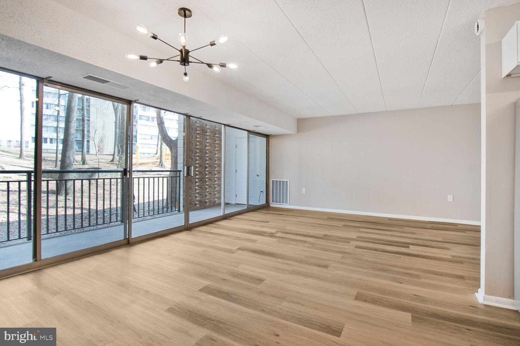 1804 Metzerott Road, Unit 106 Silver Spring, MD 20903 - Photo 3 of 15 an empty room with chandelier fan and windows