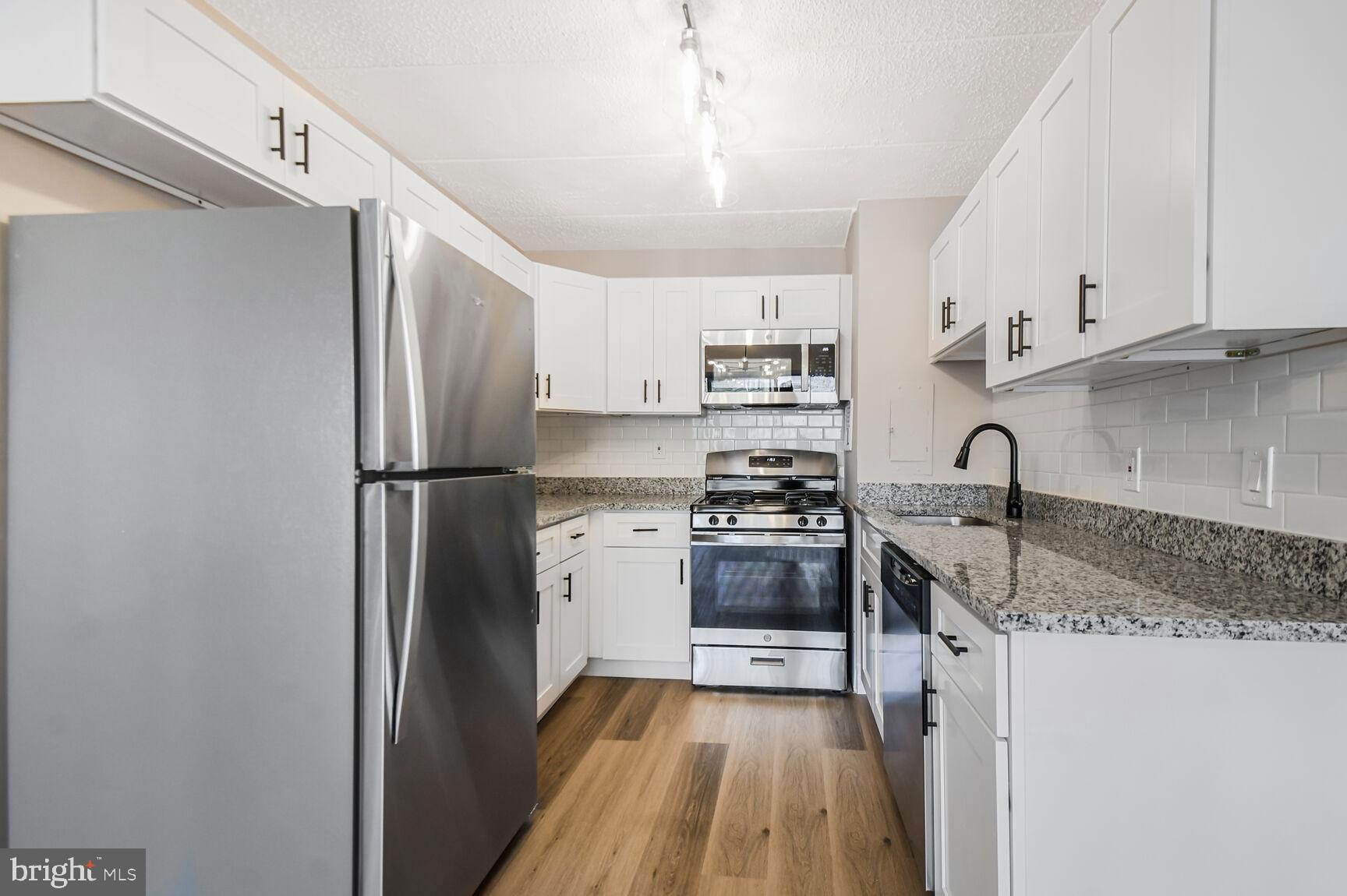 1804 Metzerott Road, Unit 106 Silver Spring, MD 20903 - Photo 7 of 15 a kitchen with stainless steel appliances granite countertop a refrigerator sink and stove