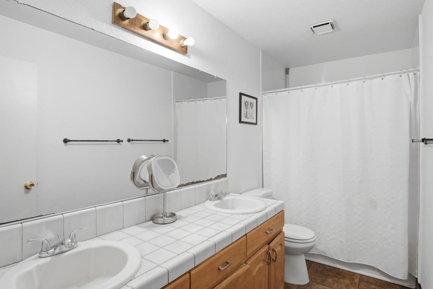 1429 Don Pedro Road Ceres, CA 95307 - Photo 12 of 21 a bathroom with a granite countertop sink a toilet and a mirror
