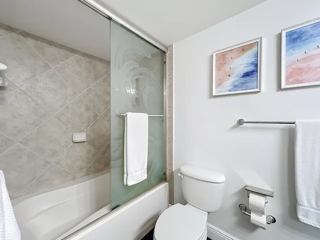 a white toilet sitting next to a bath tub and a shower