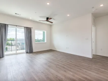 an empty room with wooden floor cabinet and a ceiling fan