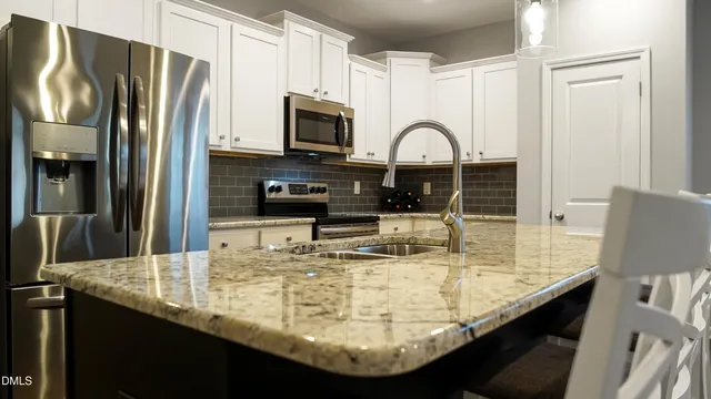 a kitchen with kitchen island granite countertop a sink a microwave and refrigerator