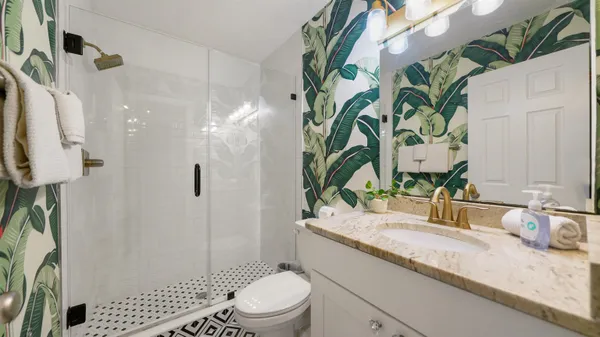 a bathroom with a granite countertop sink a toilet and shower