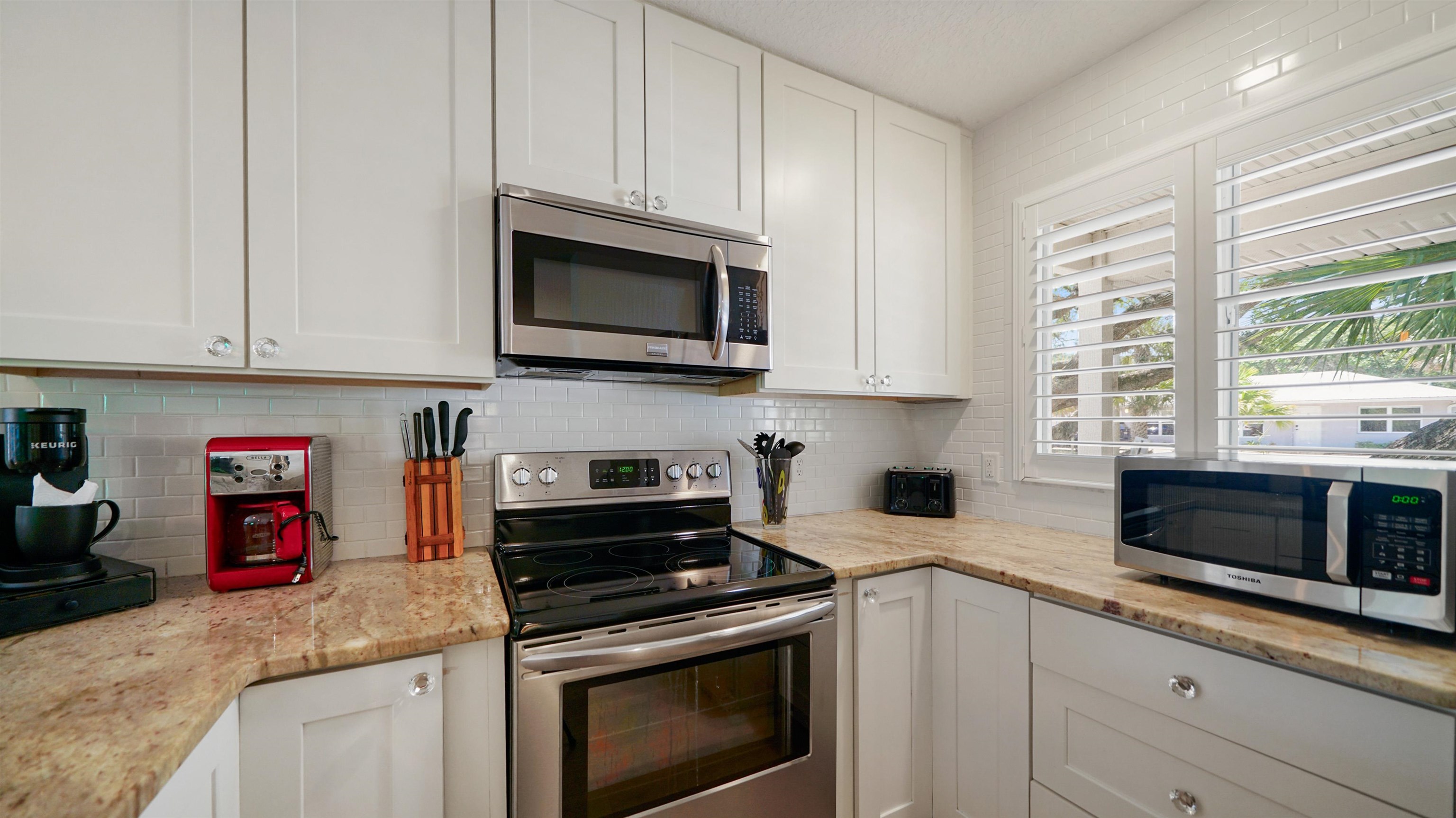 108 A Street, Unit A St. Augustine, FL 32080 - Photo 9 of 38 a kitchen with stainless steel appliances granite countertop a sink a stove a microwave and wooden cabinets