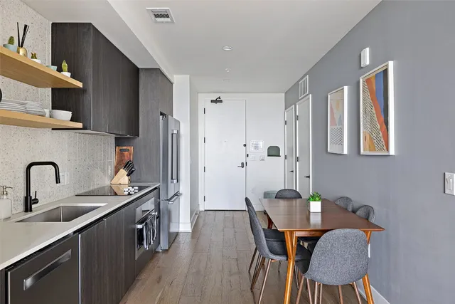 a kitchen with stainless steel appliances a table chairs and a refrigerator