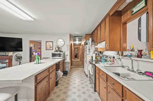 a large kitchen with stainless steel appliances a sink counter space and a window