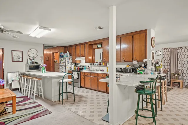 a kitchen with stainless steel appliances kitchen island granite countertop dining table chairs cabinets and a window