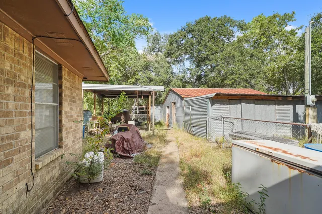 a backyard of a house with large trees and plants