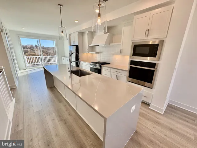 a large kitchen with kitchen island a large counter top space a sink stainless steel appliances and cabinets