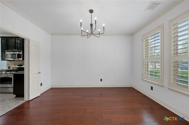 an empty room with chandelier fan and windows