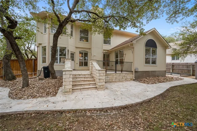 a view of a white house with a large tree