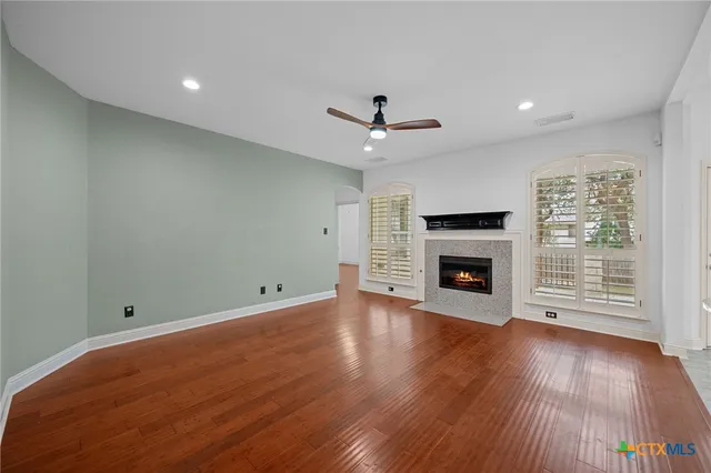 an empty room with wooden floor fireplace and windows