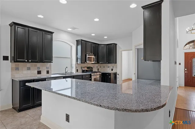 a kitchen with stainless steel appliances granite countertop a sink stove and refrigerator