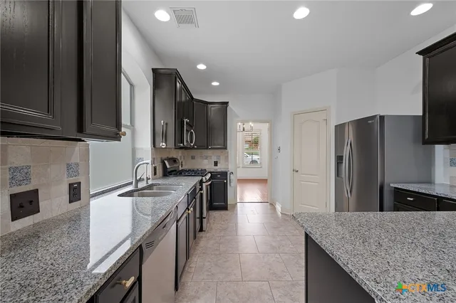 a kitchen with stainless steel appliances granite countertop a sink a stove and a refrigerator