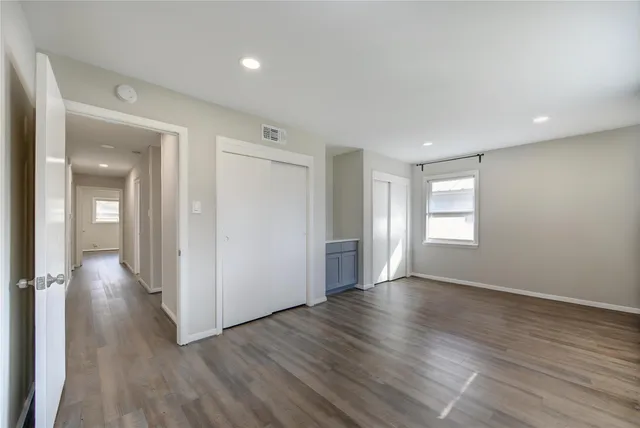 an empty room with wooden floor and windows
