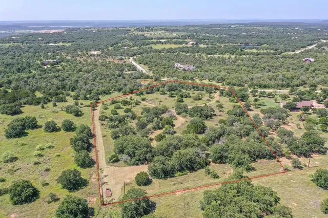 an aerial view of a houses with a yard and mountain view in back